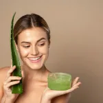 Smiling,Happy,Young,Female,Model,Holding,Aloe,Leaf,And,Jar